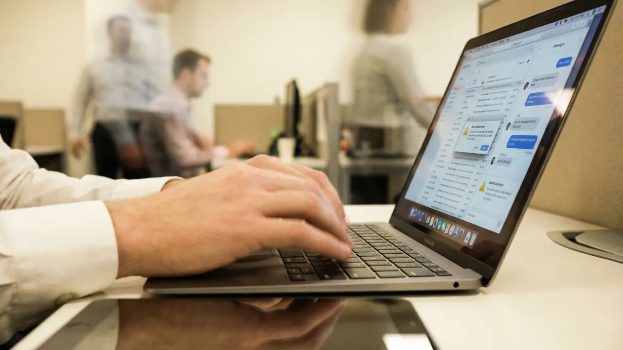 Mains d'un cadre tapant frénétiquement sur un clavier, notifications empilées symbolisant le circuit de récompense dopaminergique